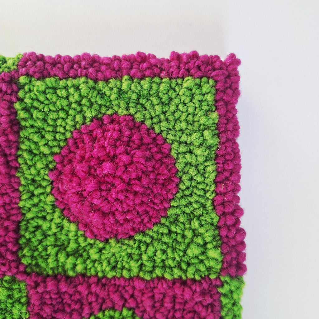 Foto detalle de cerca de cuadro realizado en punch needle. Color verde y buganvilla.