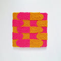 Vista frontal de cuadro de lana realizado artesanalmente en punch needle. Color rosa y mostaza.