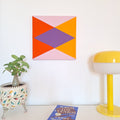 Cuadro textil realizado en patchwork de forma artesanal. Tiene formas geométricas: triángulos y rombo. Colores: naranja, morado y amarillo.